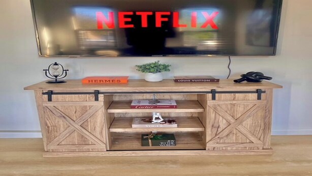 A wooden TV stand with a mounted TV displaying 'NETFLIX' in red letters.