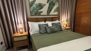 A neatly arranged bedroom with a bed, a nightstand, a lamp, and a painting on the wall. - Beauty Apartment Dominicus Breeze (Dominicus)