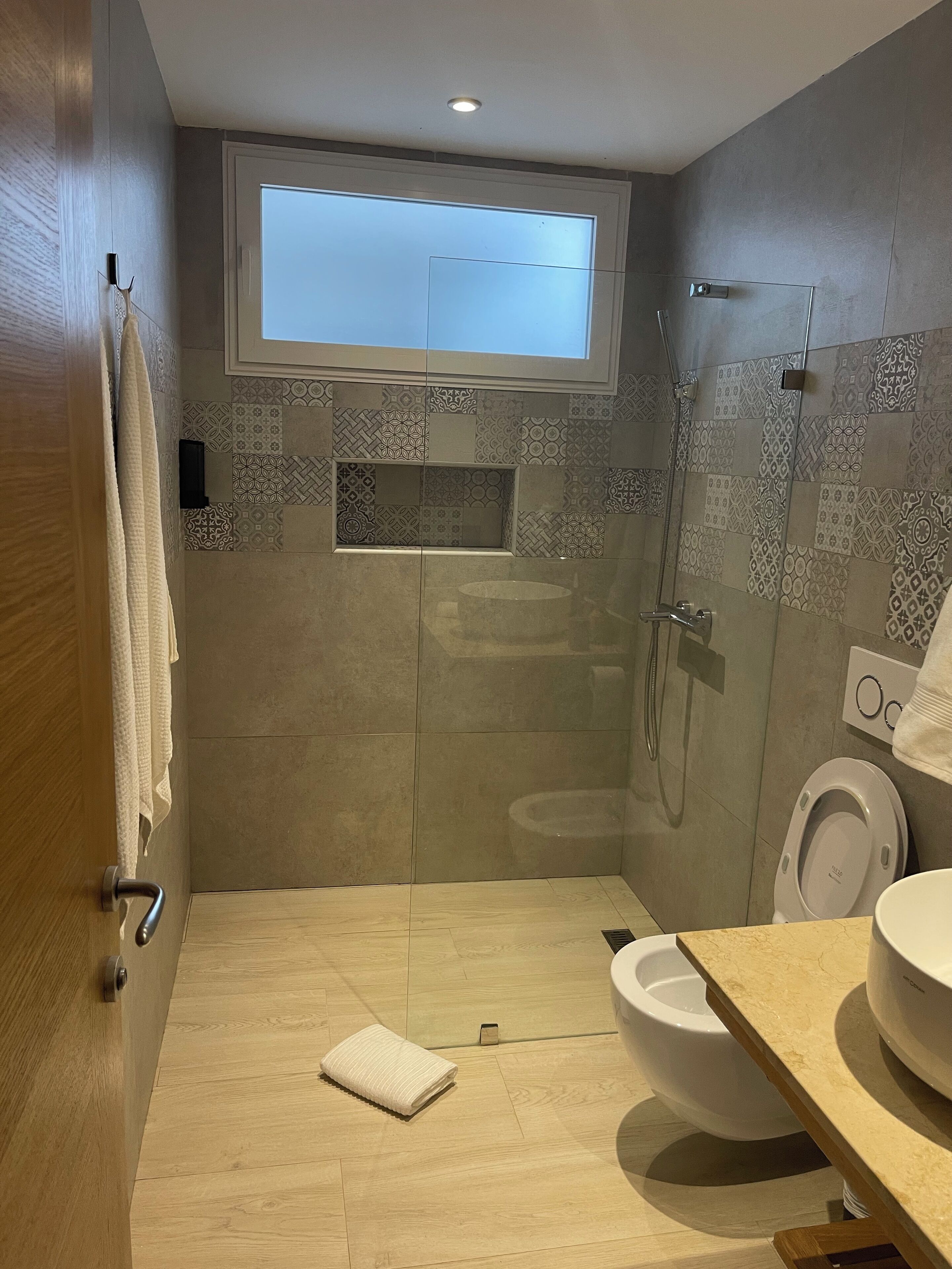 A modern bathroom with a shower, toilet, and sink.