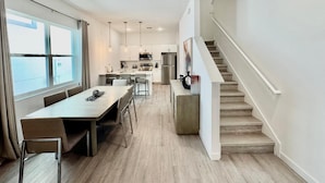 Een moderne keuken met witte kasten, roestvrijstalen apparatuur en hanglampen.