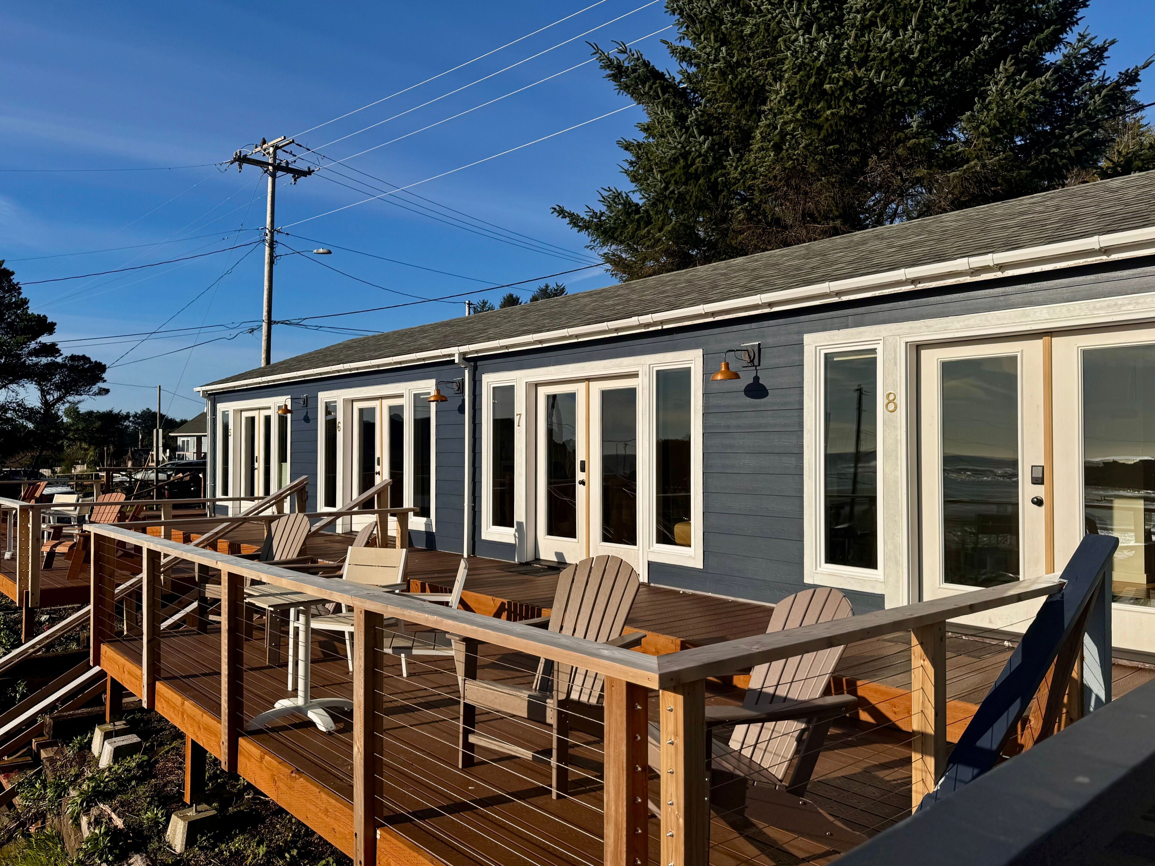 Une propriété située au bord de l’eau, dotée d’une terrasse en bois, d’un espace salon extérieur et d’un patio couvert.