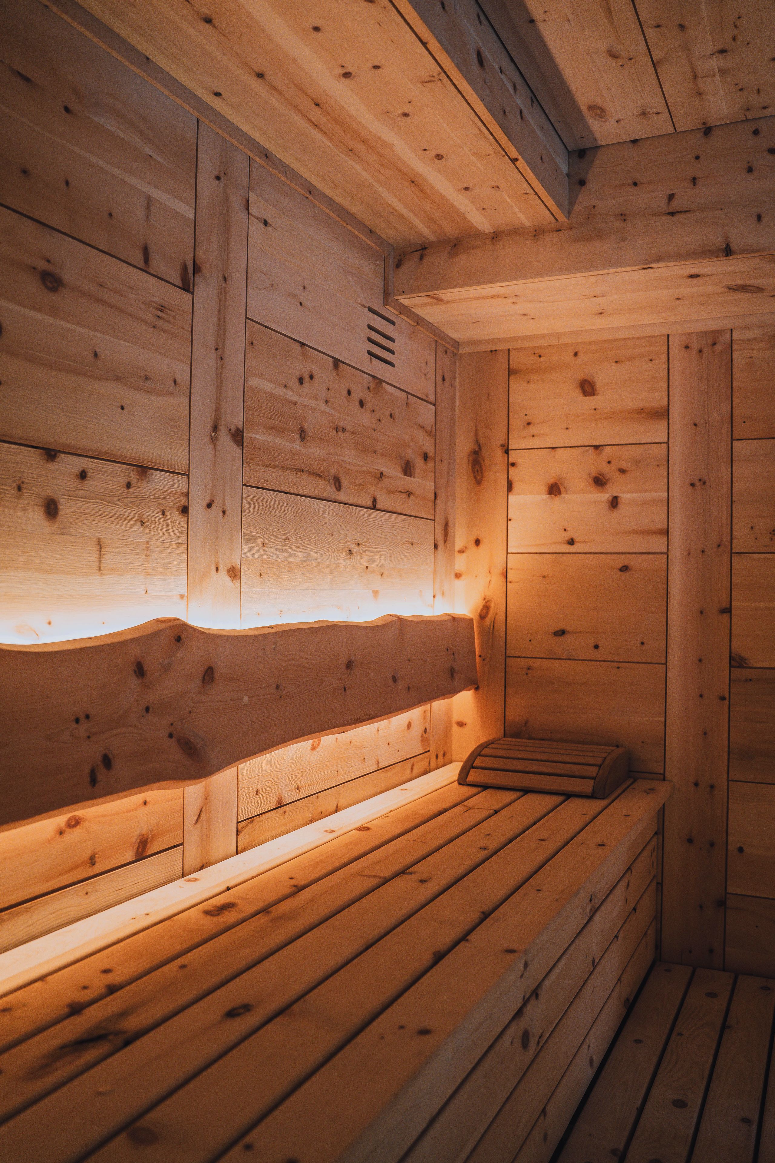 Un sauna en bois, doté de bancs et d’un plafond incliné.