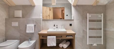 Un baño moderno con tragaluz, tocador de madera, bidé, tendedero para toallas y calentador de toallas.