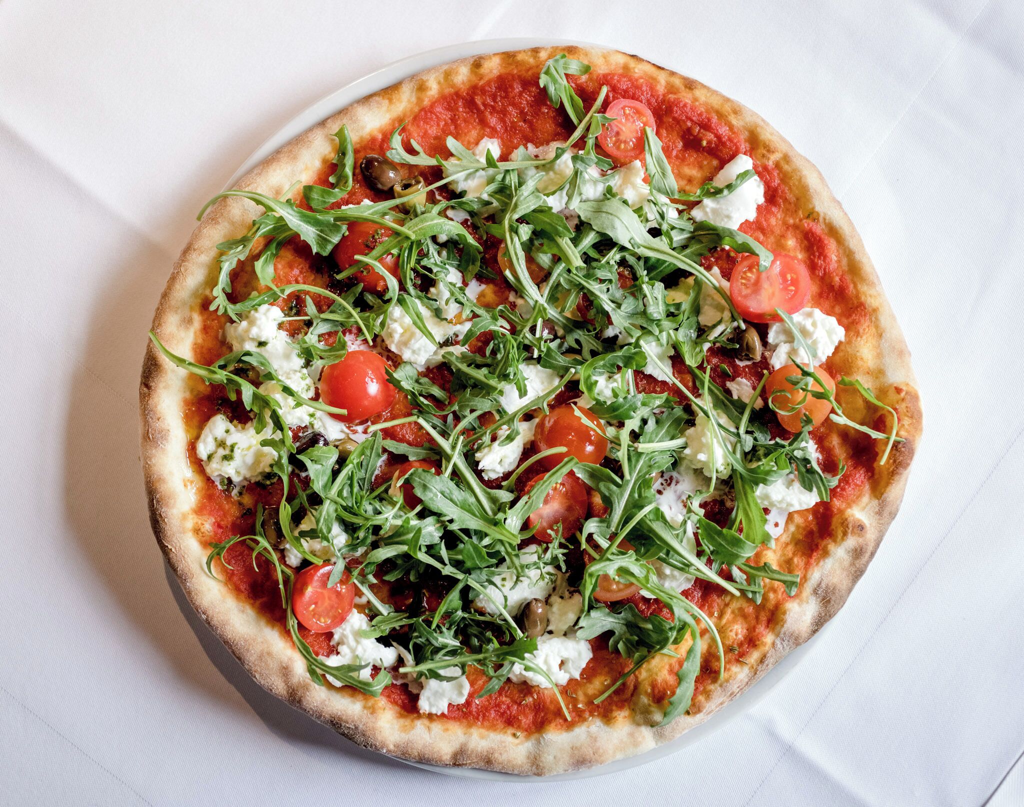 Een pizza met toppings op een wit bord.