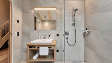 A modern bathroom with a wooden vanity, a large mirror, and a walk-in shower.