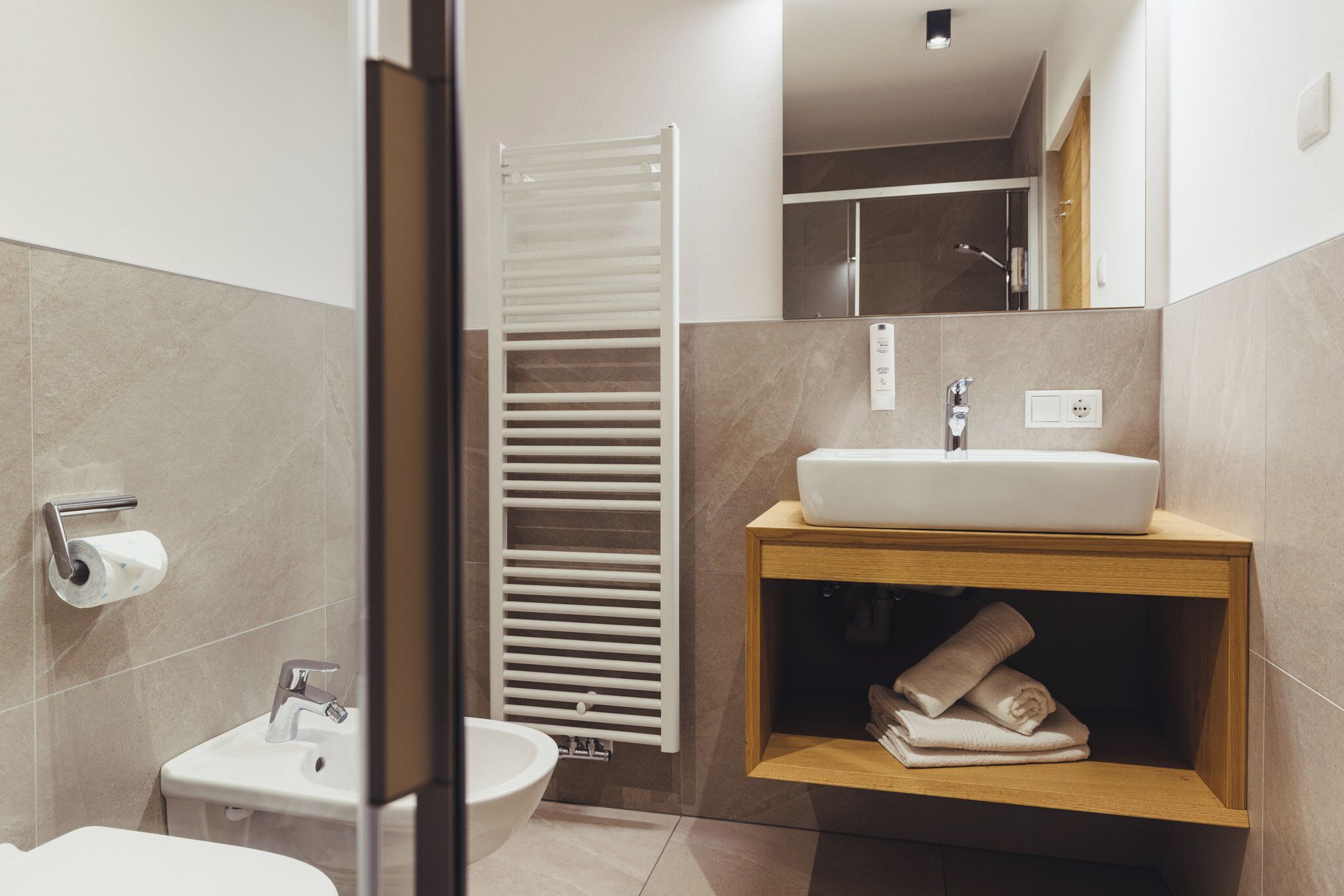 A modern bathroom with a toilet, sink, and towel rack.
