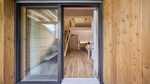 A modern interior with a wooden floor, a staircase, and a small seating area with a plant. - Hotel Schmuckhof (Chiusa)