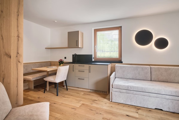 A compact living space with a kitchenette, a dining area, and a seating area. - Hotel Schmuckhof (Chiusa)