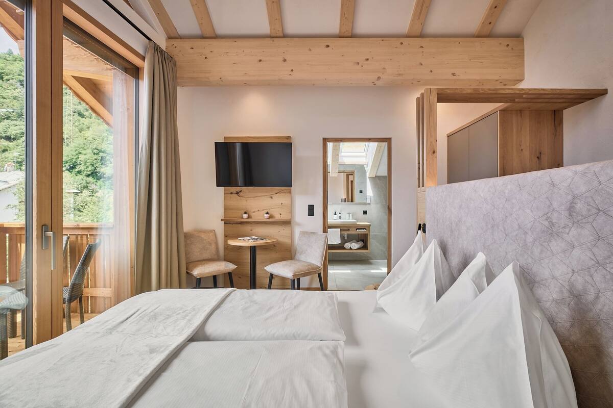 Une chambre à coucher avec un grand lit, un bureau, une chaise et un téléviseur fixé au mur.