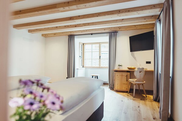 A bedroom with a bed, a desk, a chair, a window, and a television. - Hotel Schmuckhof (Chiusa)