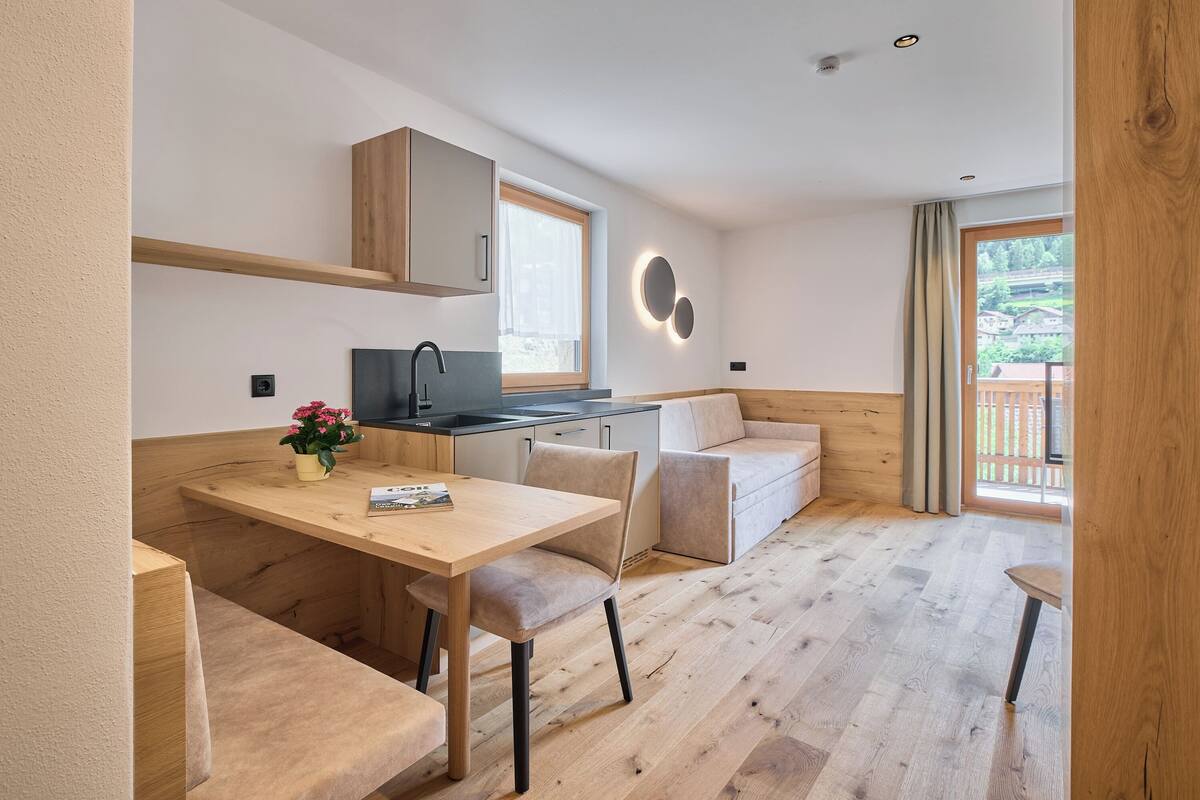 Une cuisine moderne avec des meubles en bois, un coin repas avec une table et des chaises, et un espace salon confortable avec un canapé.
