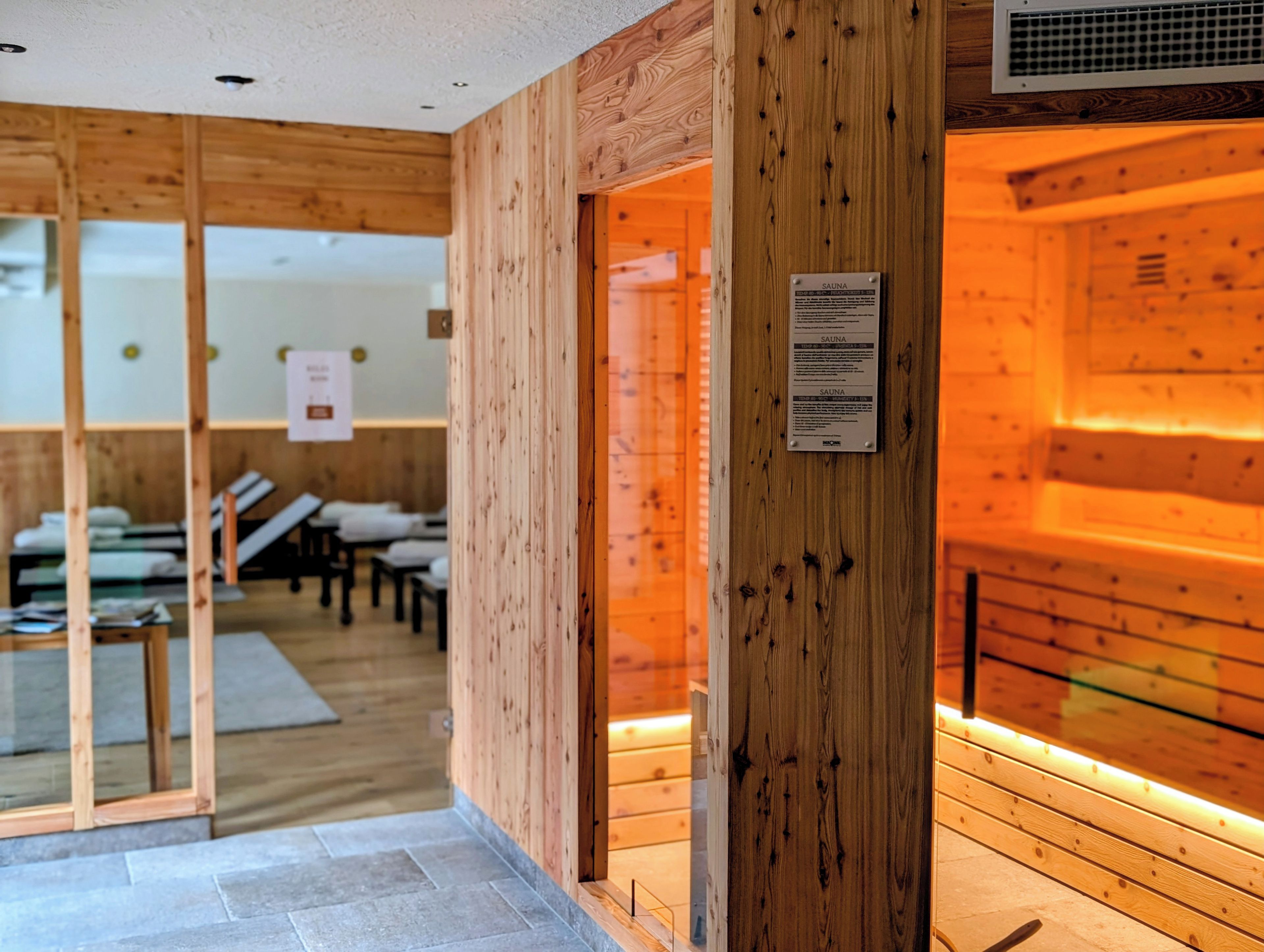 Un sauna de madera con puerta de cristal, un letrero y un banco en su interior.