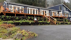 Un bâtiment à deux étages doté d’une terrasse en bois et d’un escalier menant à l’étage supérieur.