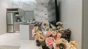 Eine moderne Küche mit Marmor-Spritzschutz, einer zentralen Kochinsel und einem wandmontierten Flachbildfernseher.