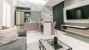 Una cocina moderna con un refrigerador empotrado, un comedor con mesa y sillas, y un televisor de pantalla plana grande montado en la pared.