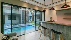 Una cocina moderna con barra, ventanas amplias y vista a una piscina.