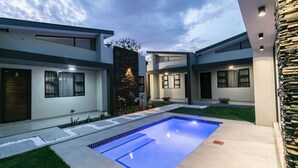 Una casa moderna con piscina, un muro de piedra y un jardín bien cuidado.