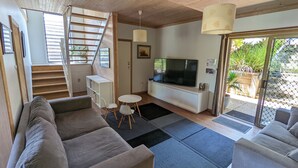 A modern living room with a staircase, a flat-screen TV, and a dining area. - Manyana Beach Getaway:
Spacious house with large deck 2 mins walk to the beach. (Manyana)
