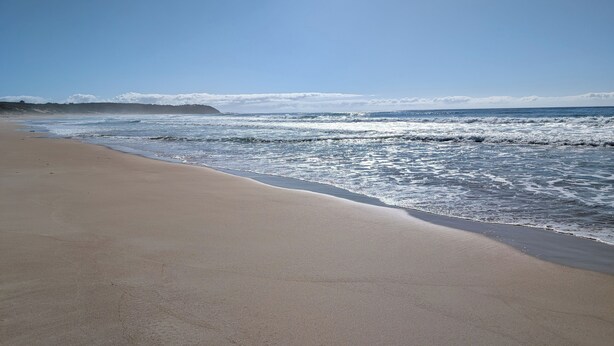 A beach with a clear sky and waves. - Manyana Beach Getaway:
Spacious house with large deck 2 mins walk to the beach. (Manyana)