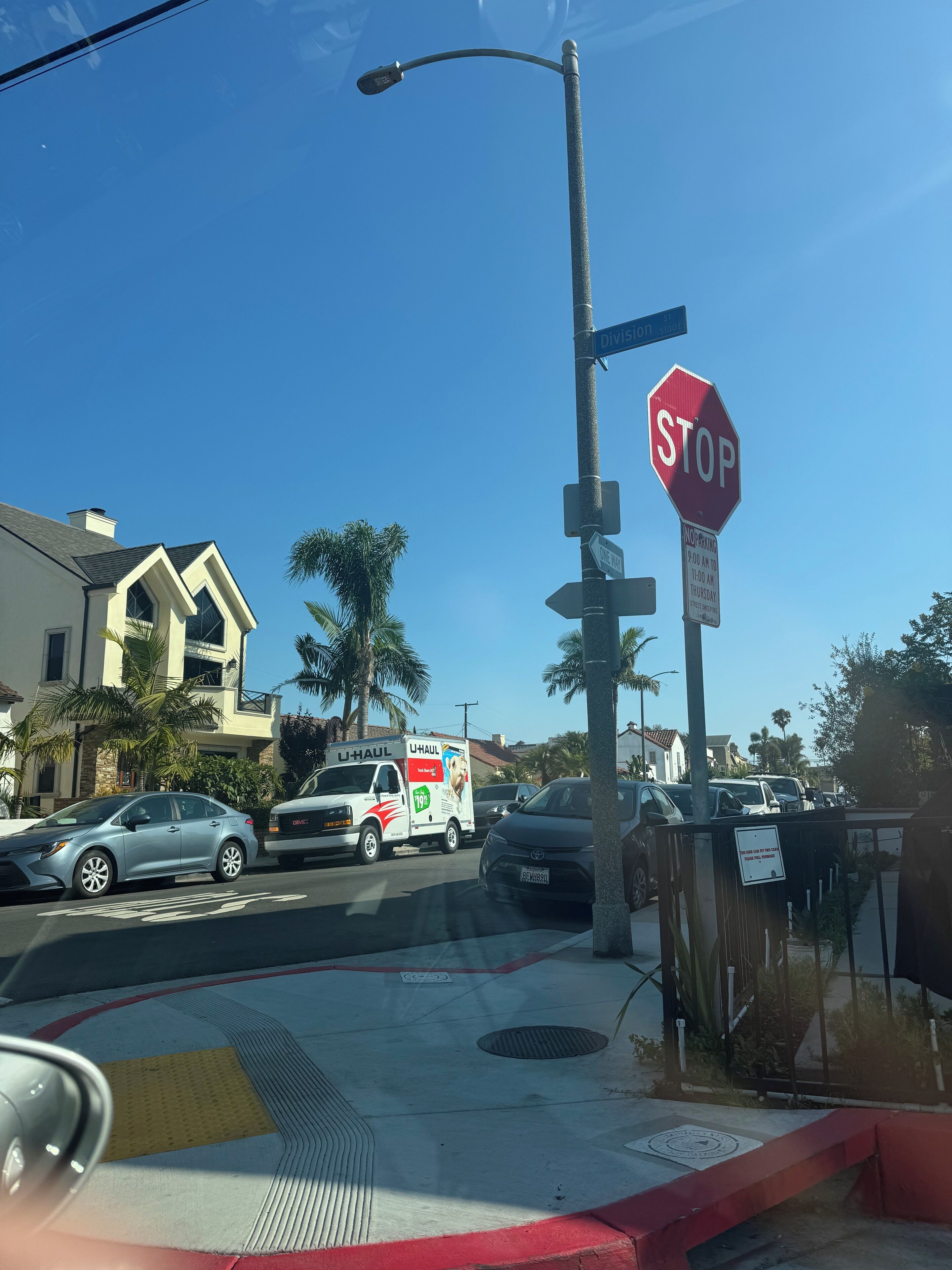 Une vue de rue avec un panneau de signalisation indiquant un arrêt obligatoire, un camion U-Haul et un immeuble d’habitation.