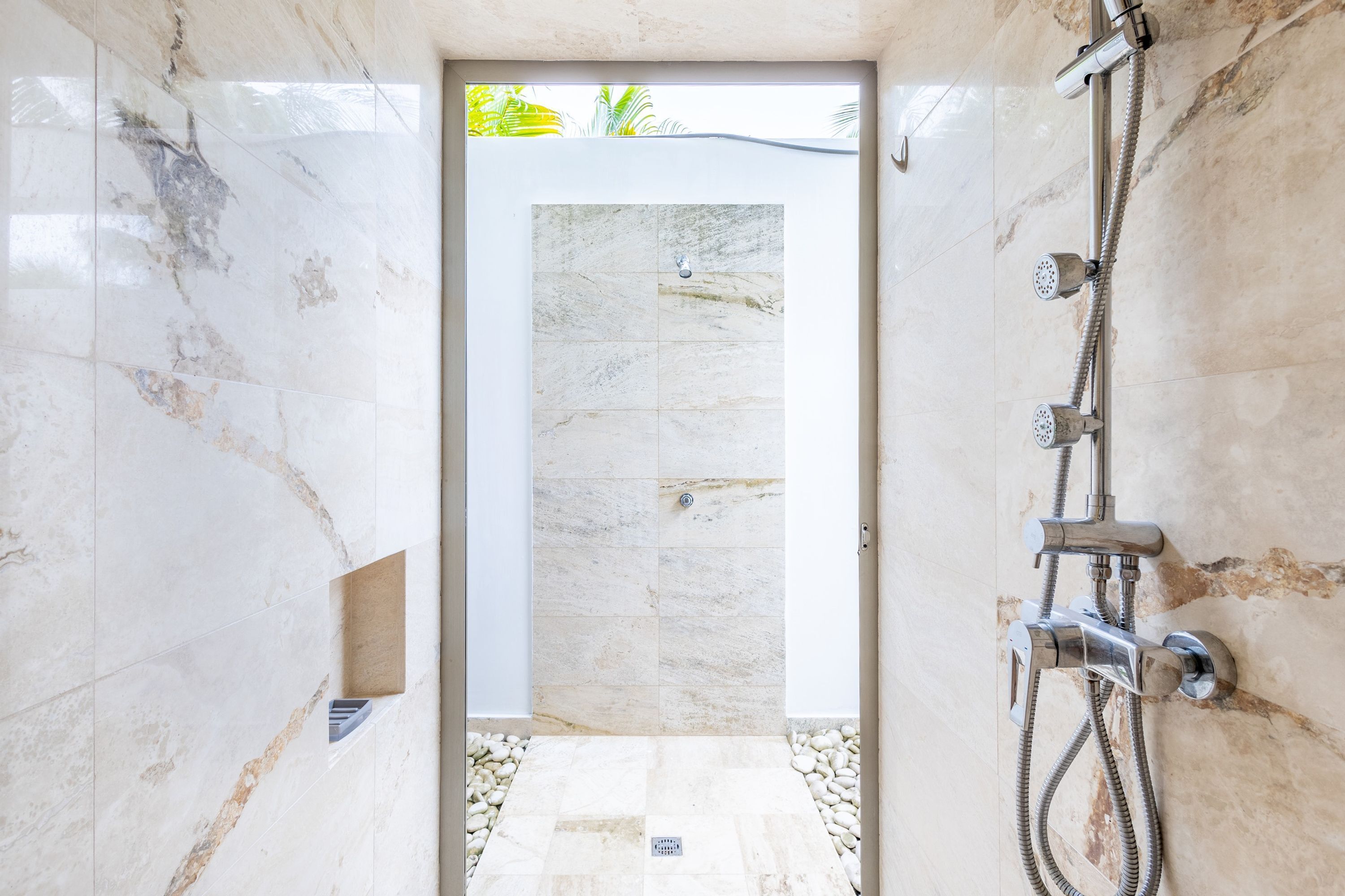 Een moderne badkamer met een douche, marmeren wanden en uitzicht op de omgeving.