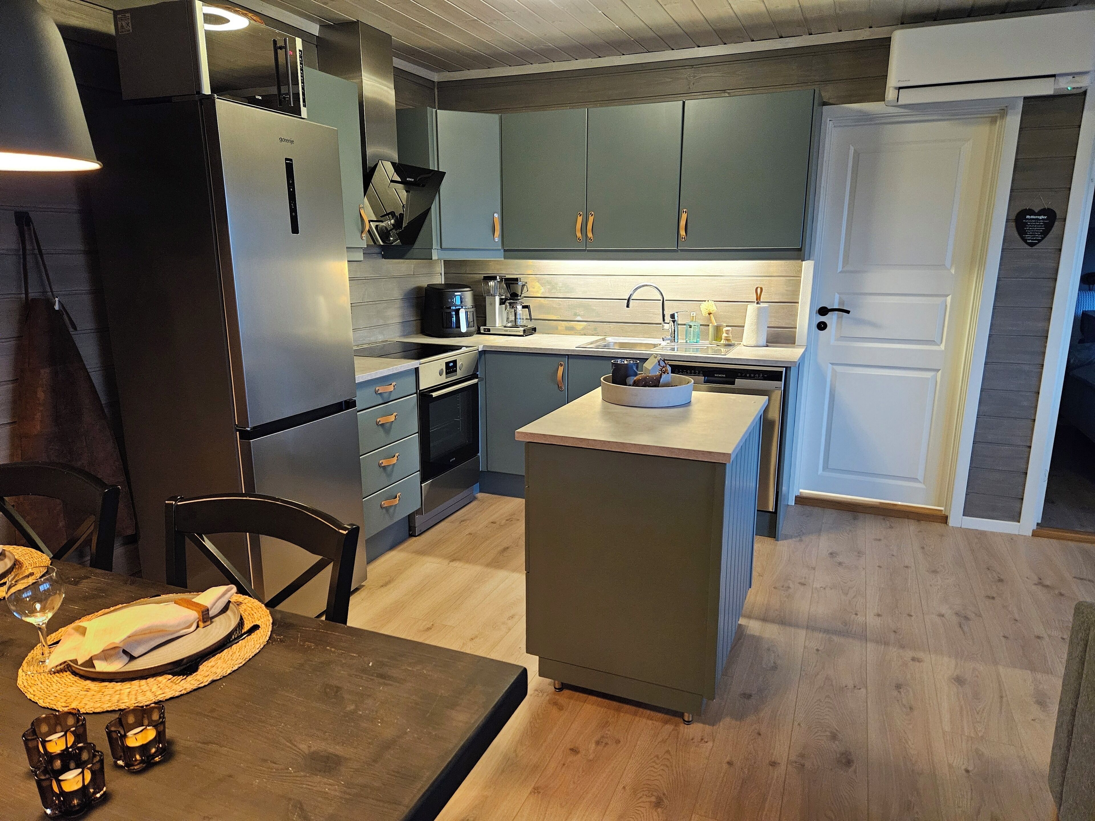 A modern kitchen with grey cabinets, a built-in oven, and a dishwasher.