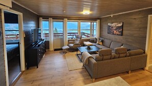 A cozy cabin interior with a wooden ceiling, a sofa, a TV, and a dining area. - Cozy 7-bed Bavallen apartment near Voss Resort – family ski base (Vestland)