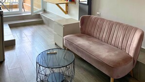 En moderne stue med sofa, sofabord i glas og træbænk.
