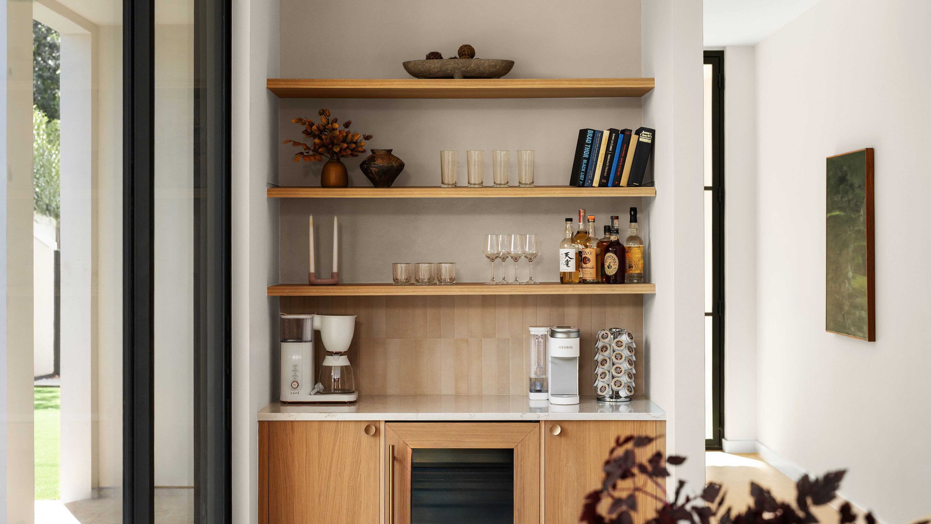 A modern kitchen with wooden shelves, a coffee machine, and a cabinet with a built-in oven.