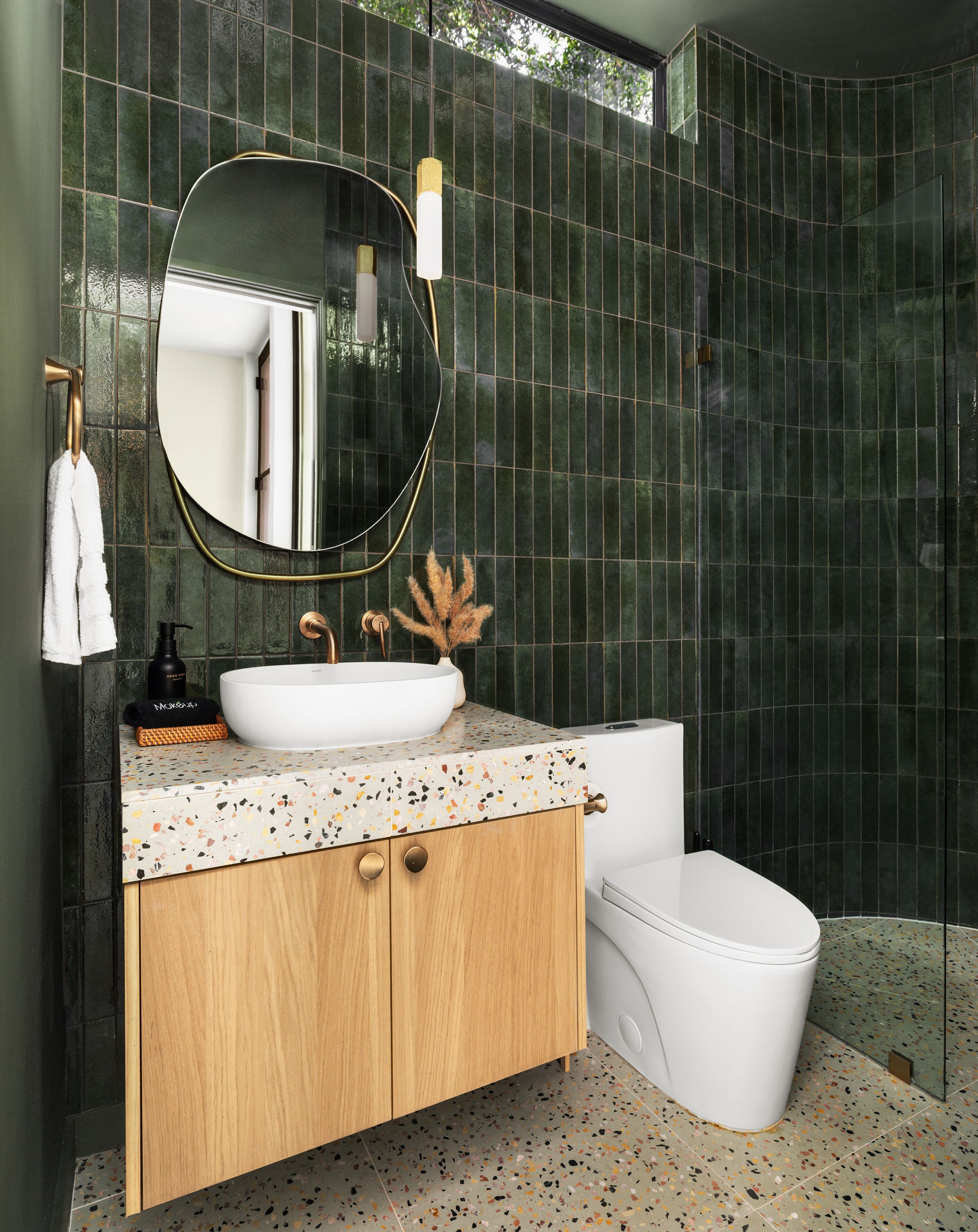 Une salle de bain moderne avec des toilettes sur pied, un miroir rond et un lavabo sur colonne.