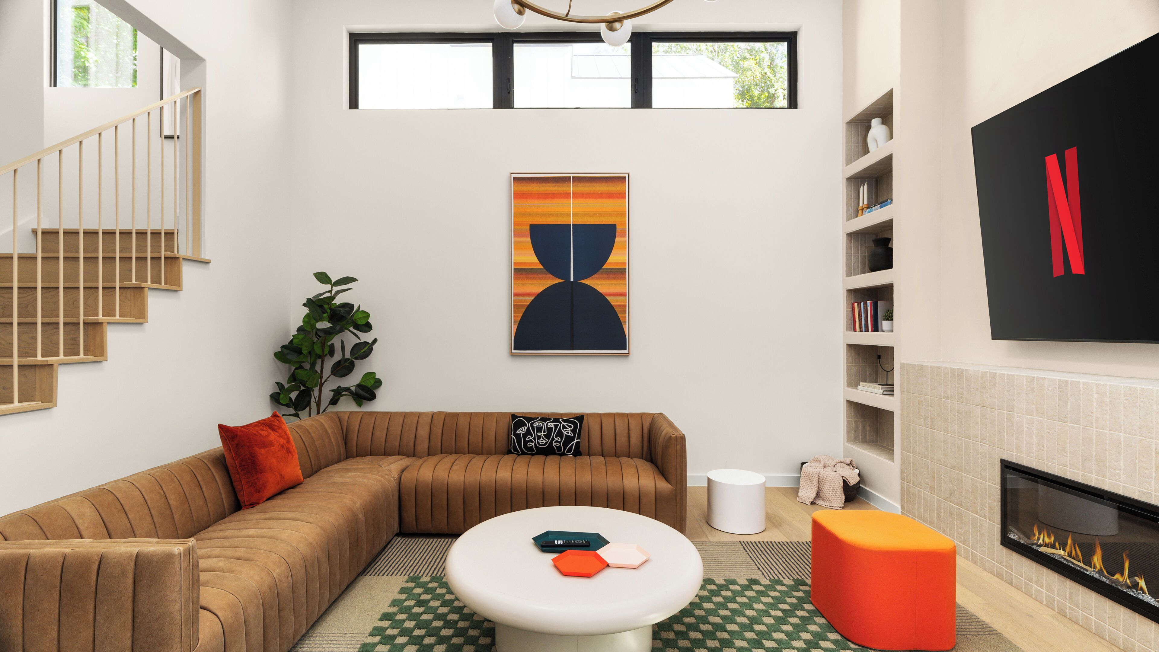 Een moderne woonkamer met een modulaire bank, een ronde salontafel, een open haard en een boekenkast.
