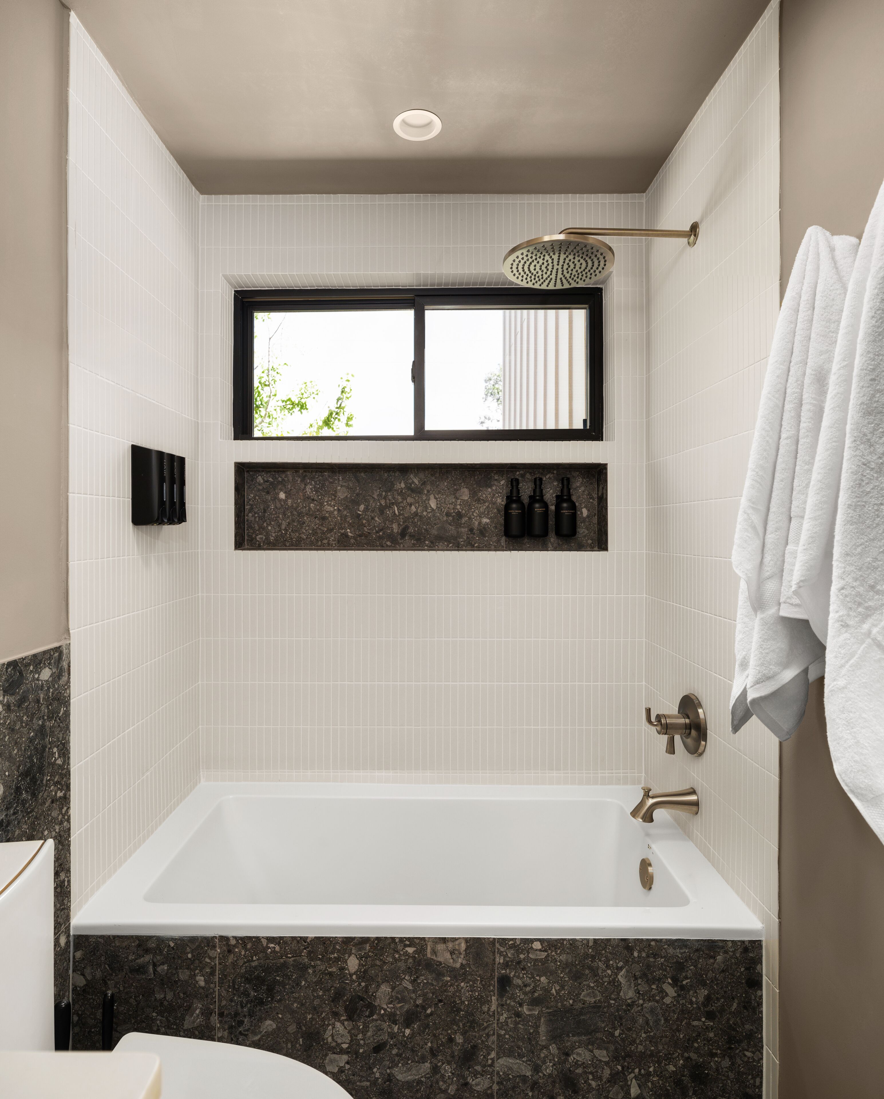 A modern bathroom with a large bathtub, a window, and a towel rack.