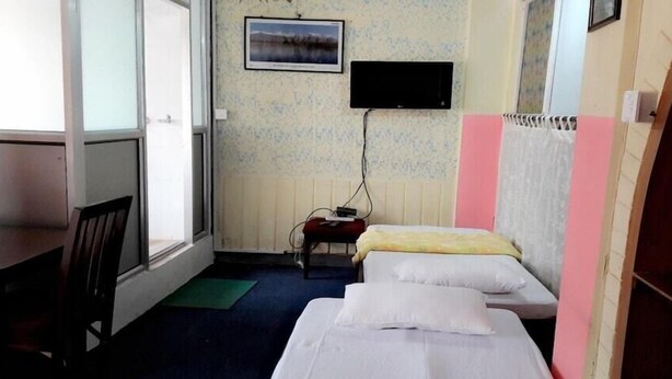 Een kleine hotelkamer met een bed, een bureau, een stoel, een televisie en een raam.