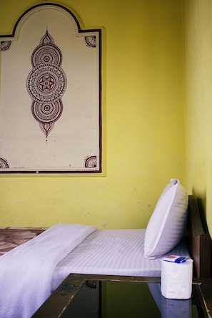 A room with a bed, a pillow, a wall-mounted decorative panel, and a toilet paper roll. - Hotel Ritu Mouria Pvt Ltd (Kathmandu)