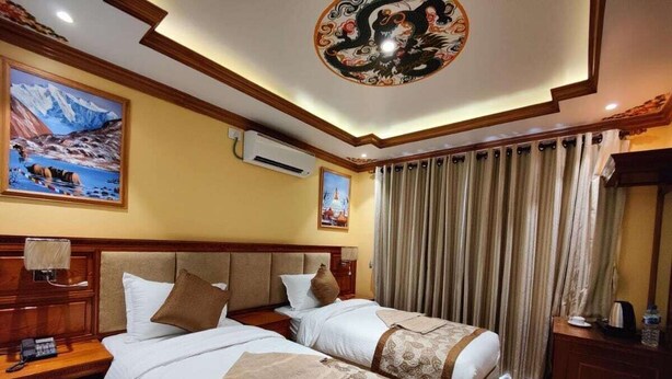 A hotel room with two beds, wooden headboards, a ceiling mural, and a large window with curtains. - Sherpa Homestay (Kathmandu)