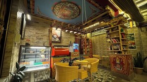 A cozy room with a coffee machine, a refrigerator, wicker chairs, and a patterned floor. - Sherpa Homestay (Kathmandu)