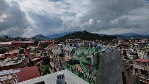 A densely packed urban area with a variety of building styles and a prominent hill in the background. - Sherpa Homestay (Kathmandu)