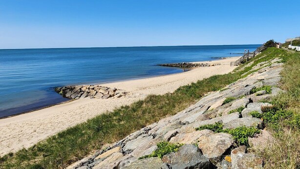 Une plage côtière avec un rivage rocheux, une plage de sable et un ciel bleu dégagé.
