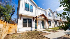A row of modern two-story houses with a covered porch and a fenced yard. - *D-town/Photobooth/Glam Rm* (San Antonio)