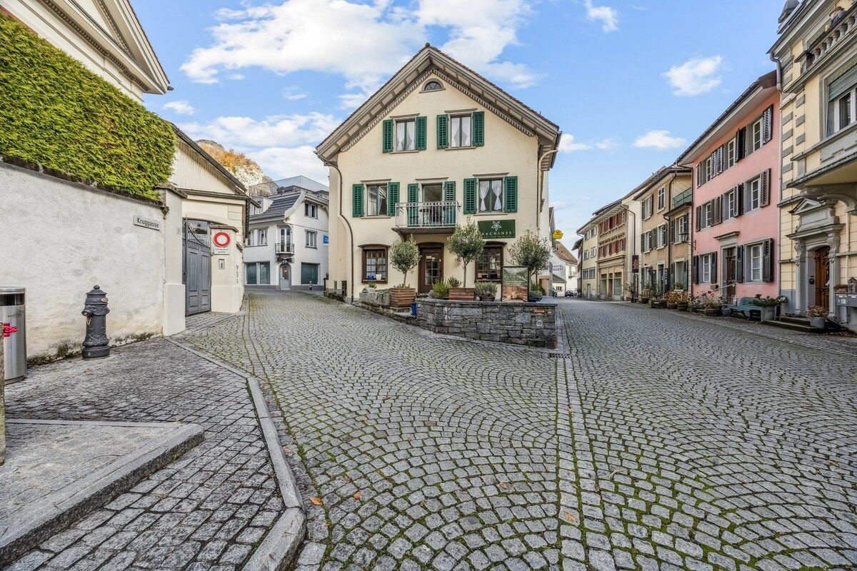 Eine Kopfsteinpflasterstraße mit historischen Gebäuden, einem Restaurantschild und einem Hydranten.