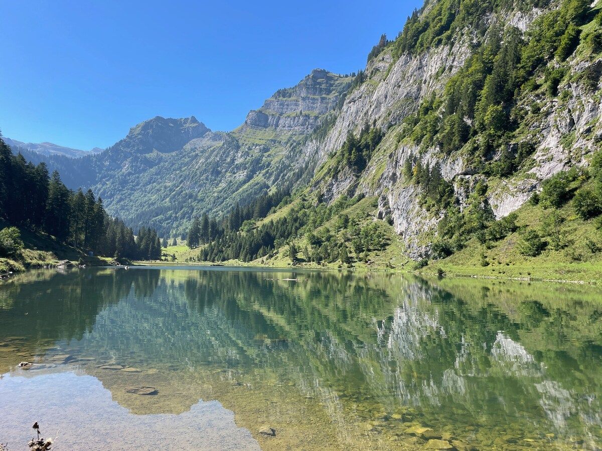 A mountain lake with clear water reflecting the surrounding landscape.