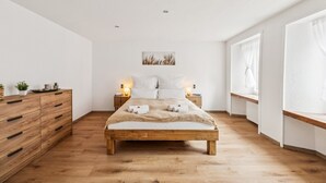 A bedroom with a wooden bed, bedside tables, a dresser, and a window with curtains. - ReMo l Old town idyll on Lake Walen #1 - Balcony I near station + highway I parking lot (Weesen)