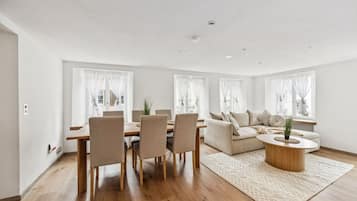 Ein modernes Wohnzimmer mit Essbereich, ausgestattet mit einem Holztisch, Stühlen, einer Couch und einem Couchtisch.
