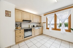 Una cocina con armarios de madera, una estufa y una ventana con cortinas blancas.