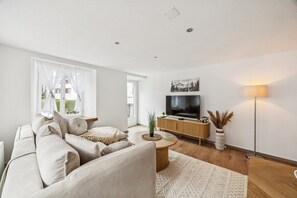 A modern living room with a sofa, TV, and a lamp. - ReMo I Old town idyll on Lake Walen #1 | Mountain (Weesen)
