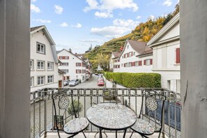 A balcony with a tiled table and chairs overlooking a street with parked cars and houses. - ReMo I Old town idyll on Lake Walen #1 | Mountain (Weesen)