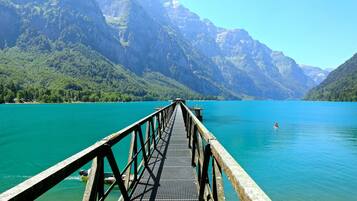 Un muelle de madera que se adentra en un lago turquesa con montañas al fondo.