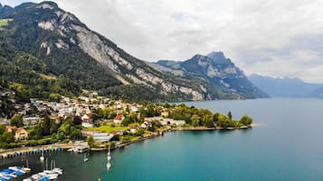Eine Stadt am Seeufer mit einem Jachthafen, Häusern und Bergen im Hintergrund.