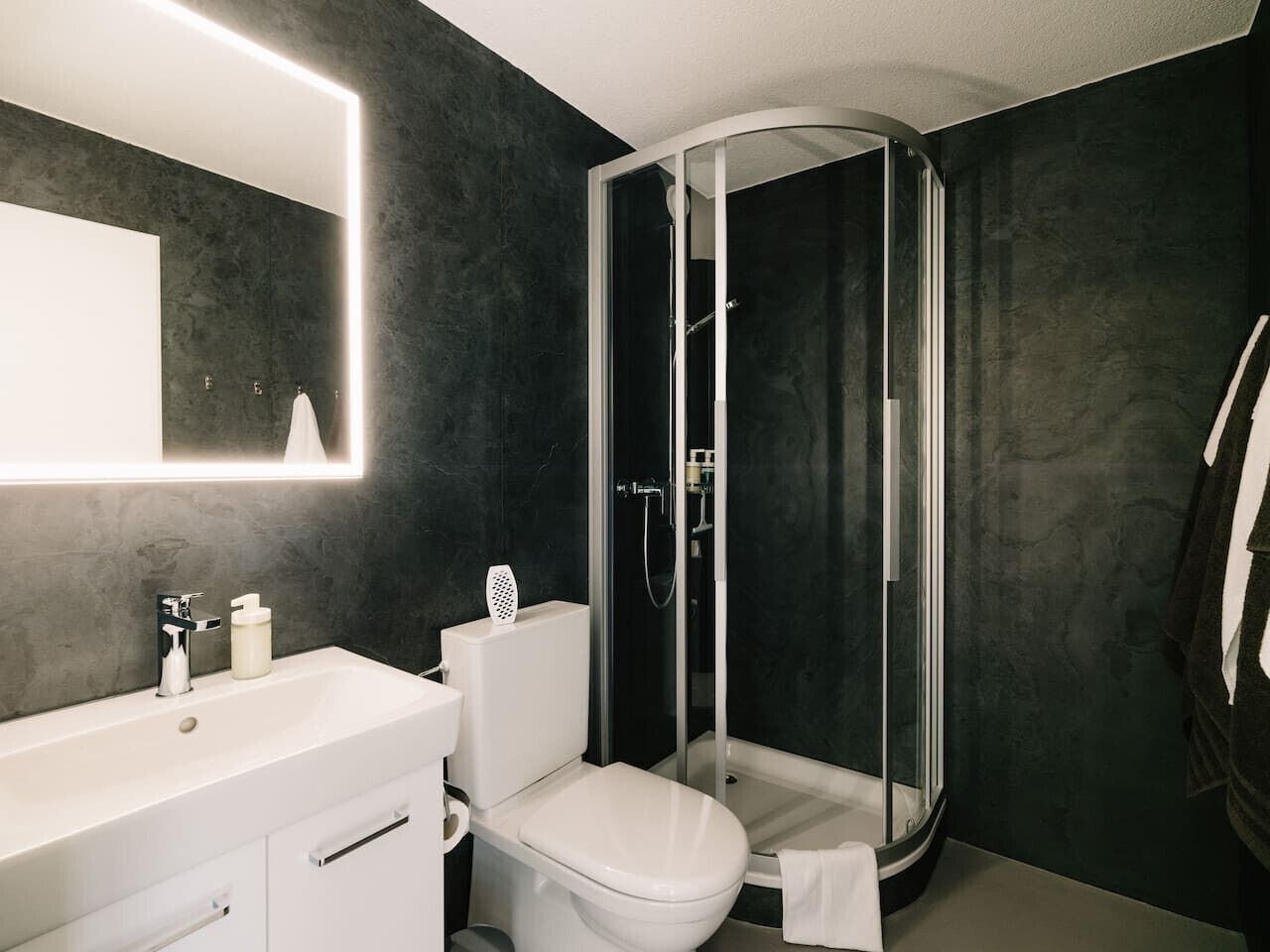 Une salle de bain moderne avec un lavabo blanc, des toilettes et une douche à parois de verre.