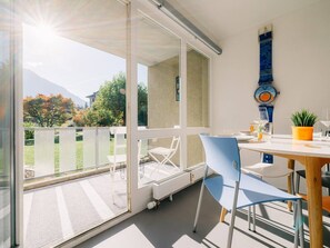 Un balcon avec une table, des chaises et un pot de fleurs.